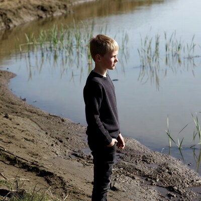 Boy standing by lakeside
