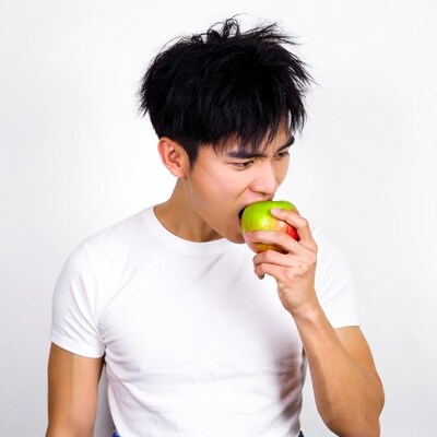 Asian man biting green apple