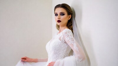 Bride in lace gown against white wall