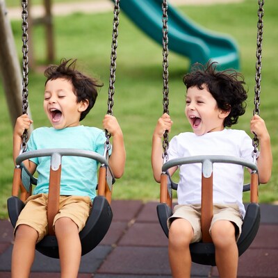 Two boys laughing on playground swings