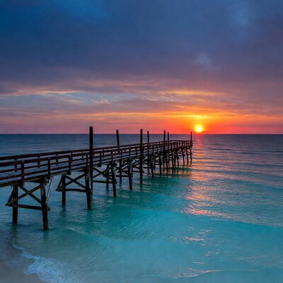 Pier extending into ocean at sunset