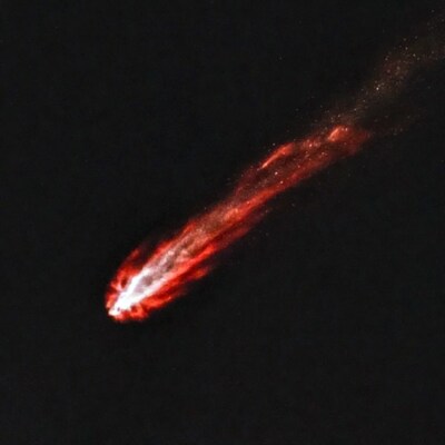 Bright red comet streaking across night sky