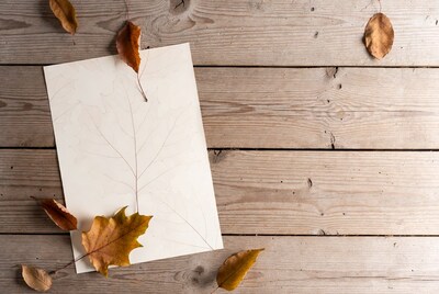 Blank paper with autumn leaves on wood