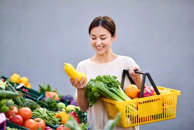 Asian woman holding yellow squash at market