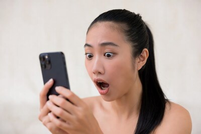 Asian woman shocked looking at phone