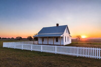 White farmhouse at sunset with picket fence