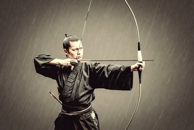 Asian man shooting Japanese bow