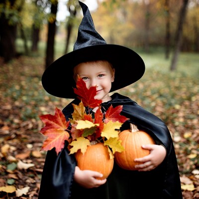 Girl in witch costume holding pumpkins