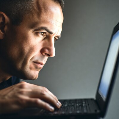 Man typing on laptop profile view