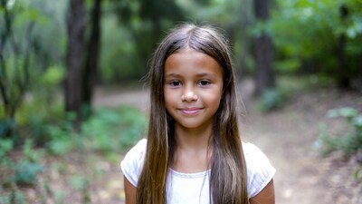 Smiling mixed-race girl in forest