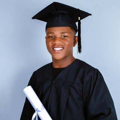 African-American boy in graduation gown with diploma