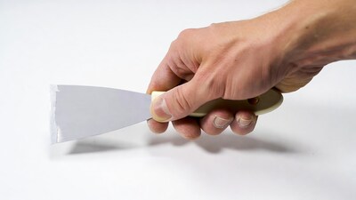 Man's hand holding putty knife