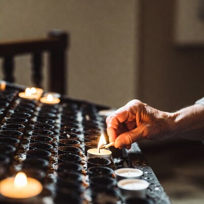Elderly hand lighting candle in church