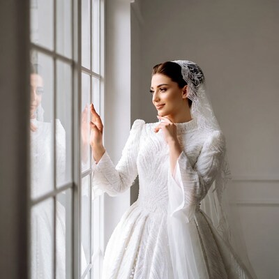 Bride in white gown by window
