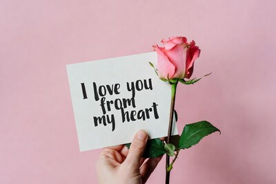 Hand holding rose with I love you card