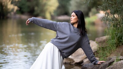 Woman posing by river in gray hoodie