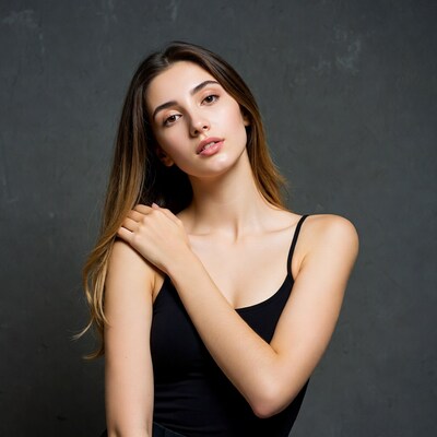 Woman in black tank top against gray wall