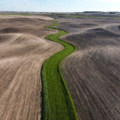 Winding green path through rolling plowed fields