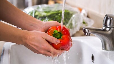 Woman washing red bell pepper