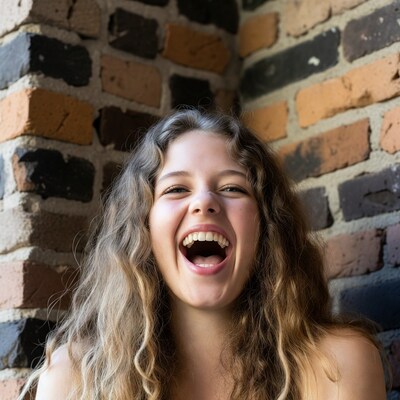 Girl laughing against brick wall