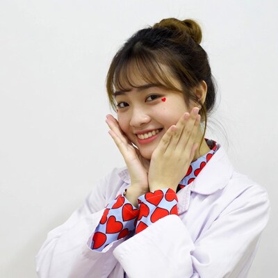Asian woman in lab coat making heart face