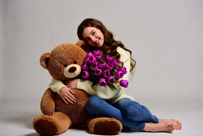 Woman hugging teddy bear with purple tulips