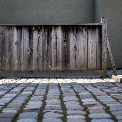 Weathered wooden fence on cobblestone pavement