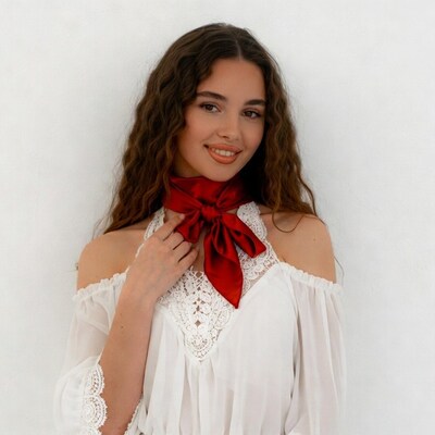 Woman in white off-shoulder top with red scarf