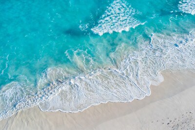 Turquoise waves crashing on white sand beach