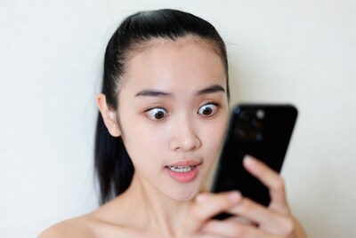 Asian woman surprised looking at phone