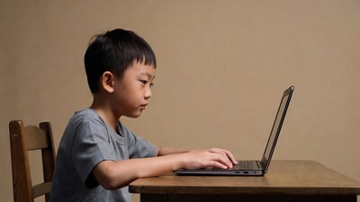Asian boy typing on laptop