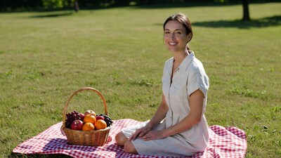 Woman sitting with fruit basket on picnic blanket