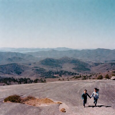 Boy and girl running hand-in-hand on mountain