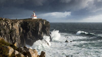 Lighthouse on cliff with crashing waves