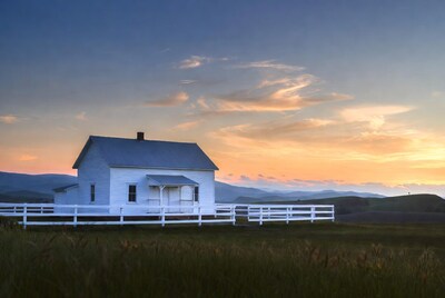 White farmhouse at sunset with mountains