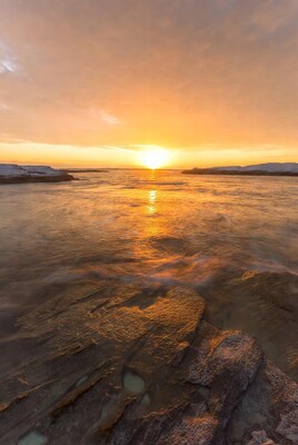 Sunset over snowy coastal rocks