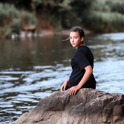 Girl sitting on rock by river