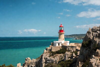 Red lighthouse on cliff overlooking sea