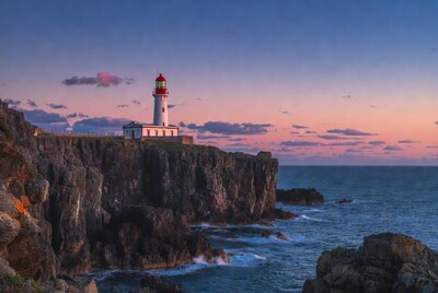 White lighthouse on cliffs at sunset