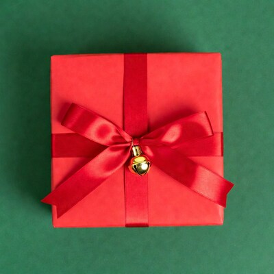Red gift box with gold bell on green background