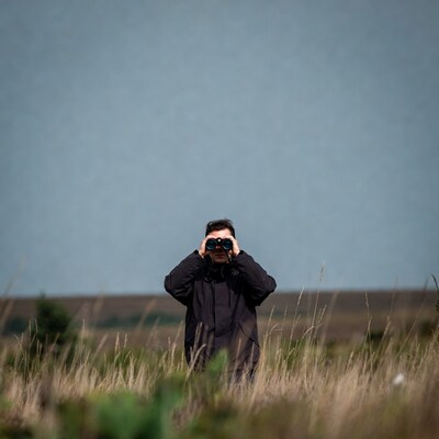 Man using binoculars in tall grass