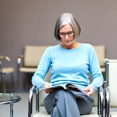 Elderly woman reading magazine in waiting room