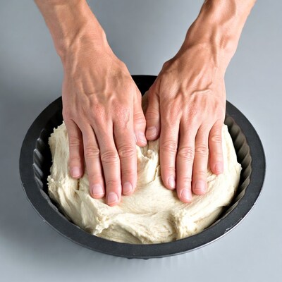 Hands kneading dough in pan