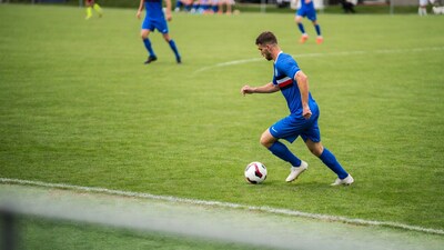 Soccer player kicking ball on field