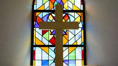 Wooden cross in front of stained glass