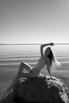Woman posing on rock by water