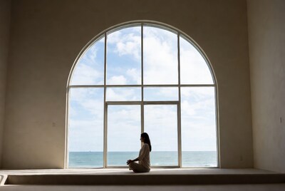 Woman meditating by large window