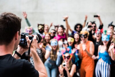 Photographer capturing masked party crowd