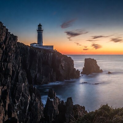 Lighthouse on Rocky Cliff at Sunset