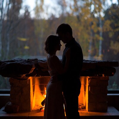 Couple embracing by fireplace